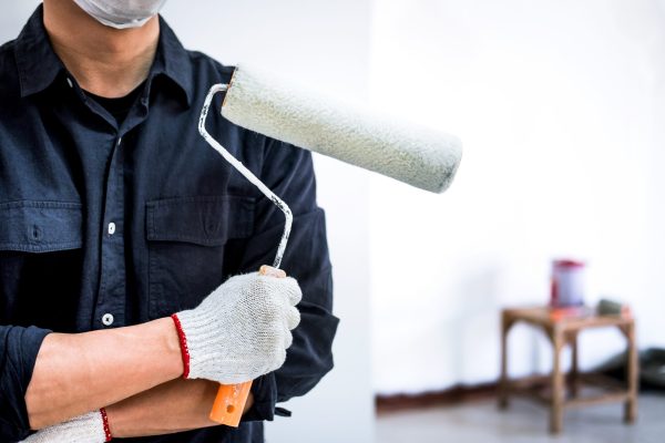 Male Painter with arm crossed holding paint roller, Interior working with paint roller in room, shape and structure.